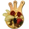 Mini tabla de madera circular sirviendo una porción individual de quesos, carnes frías, manzana, fresa y nueces.