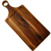 Tabla de madera de teca natural en ángulo diagonal, destacando un nudo oscuro en la veta central y el orificio redondo en el mango.