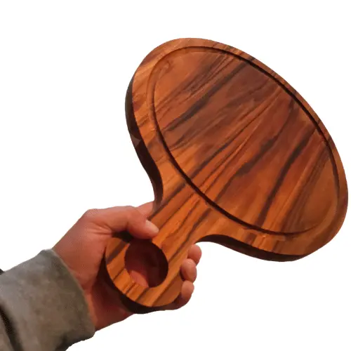Mano de una persona sosteniendo firmemente en el aire una gruesa tabla redonda de madera de teca por el mango.
