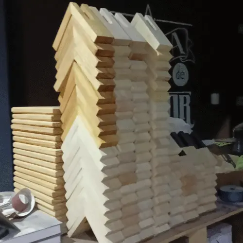 Gran torre de decenas de servilleteros de madera de pino apilados ordenadamente en un taller de carpintería.